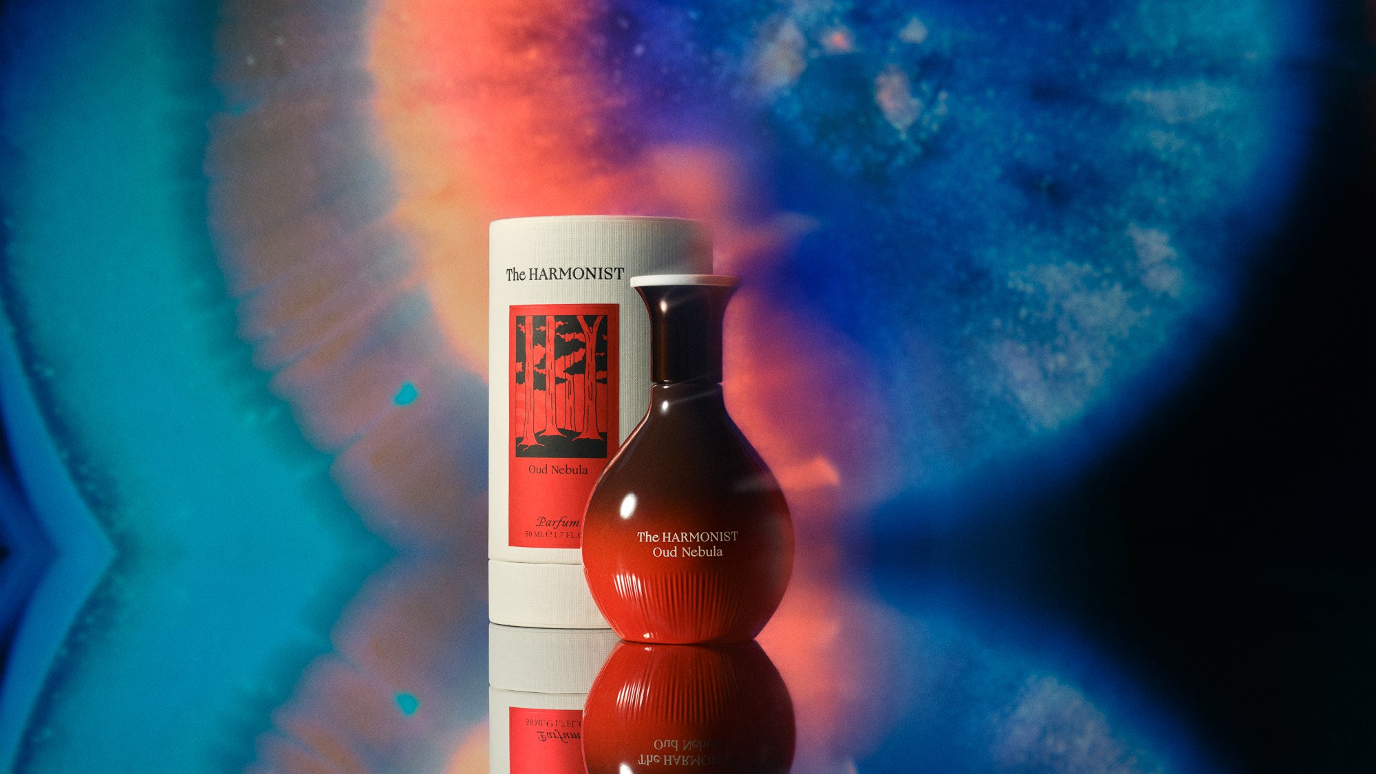 Parfumflakon Oud Nebula in rot mit geripptem Design und weißer Verpackung vor blau-rotem Hintergrund