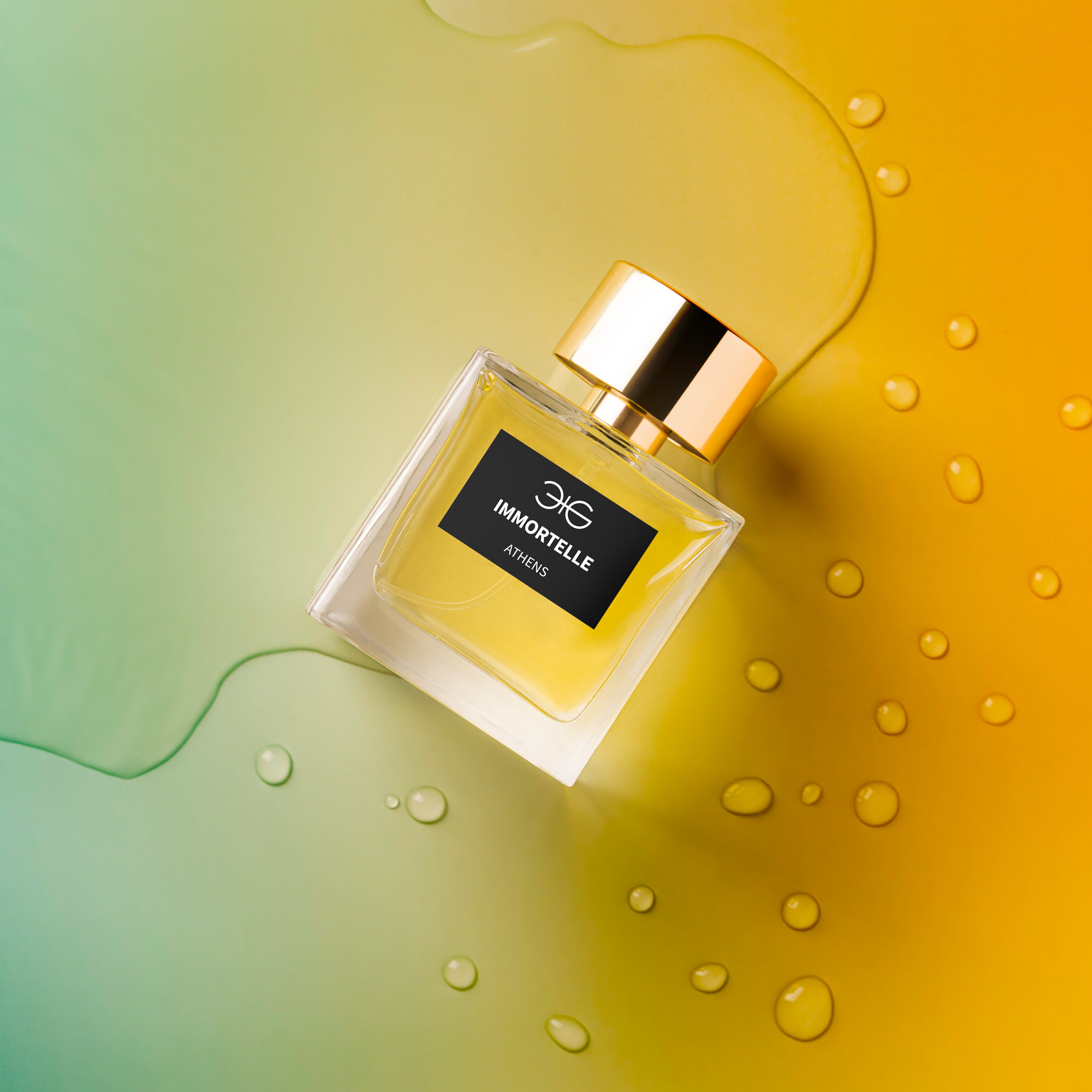 Parfumflakon Immortelle von Manos Gerakinis mit goldenem Deckel auf grün-gelbem Hintergrund mit Wassertropfen