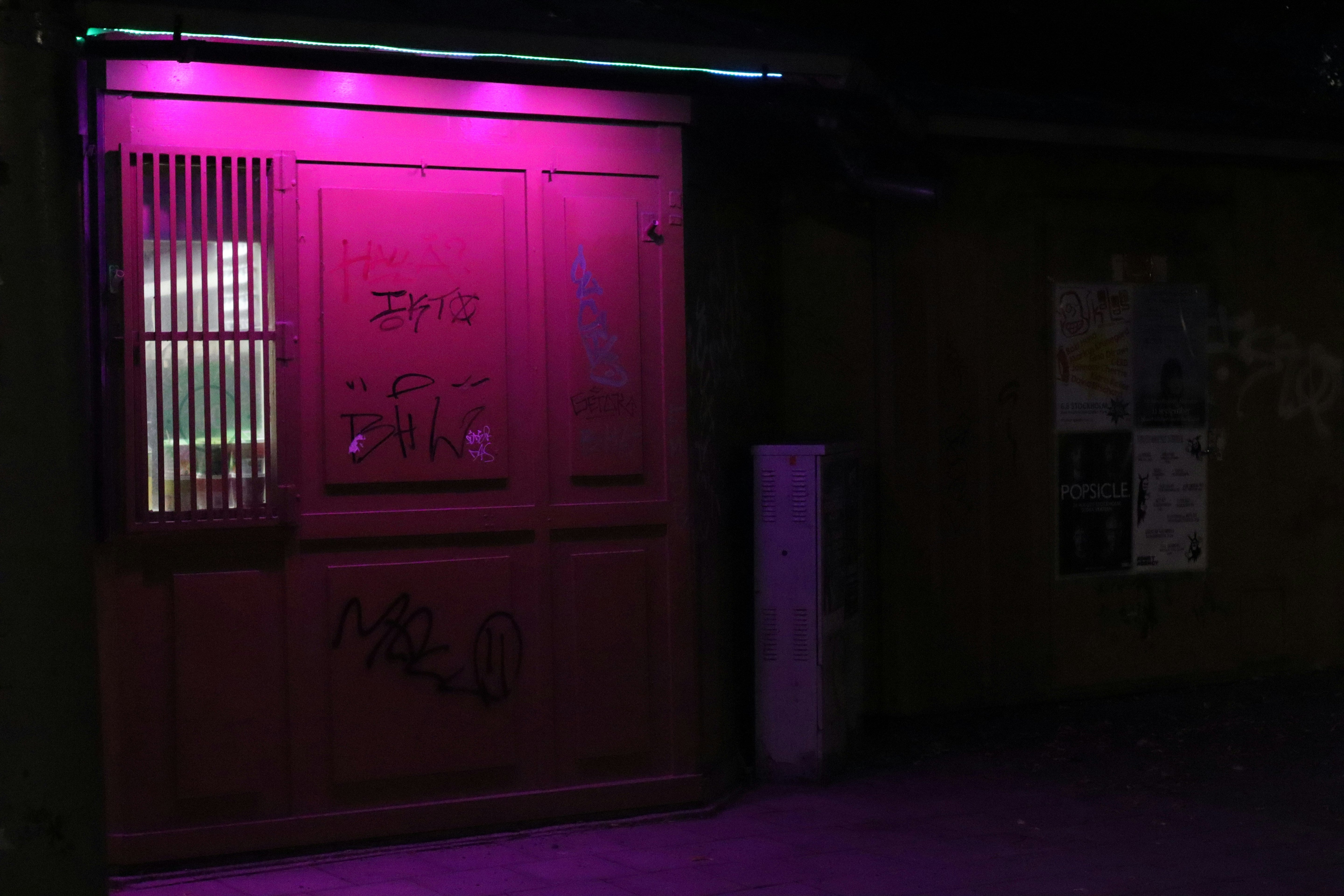 Pink beleuchtetes Schaufenster mit Graffiti in nächtlicher urbaner Straßenszene